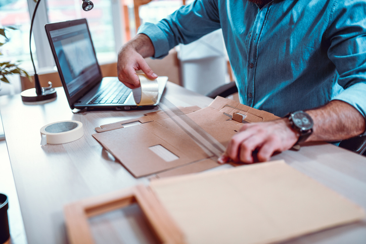 Office Worker Using Adhesive Tape To Construct A Cardboard Package - All Audiences...Not Created Equal