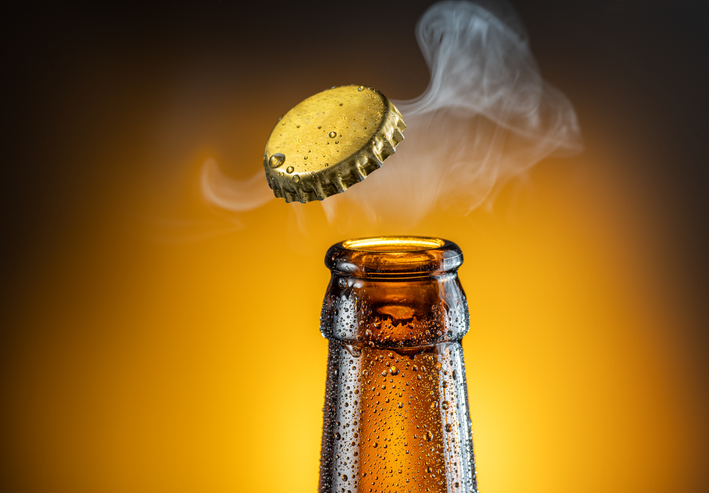 Opening Of Cold Beer Bottle Gas Output And Bottle Cap In The Air. Isolated On A Yellow Background. - Branding, Connec...