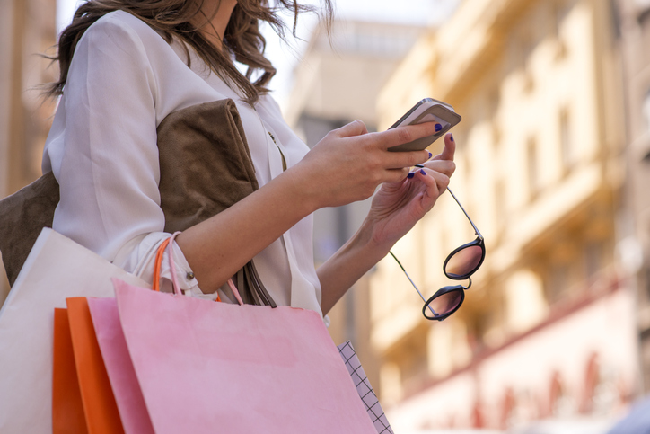 Women Carrying Shoppings Bags And Using Smartphone - Customer Retention & The Struggle For Loyalty
