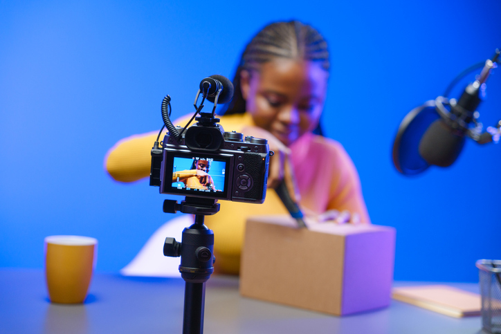 A Dark Skinned Vlogger Girl In Her Studio Starts Unpacking A Cardboard Box. - Influencer Marketing: 7 Steps For A Suc...