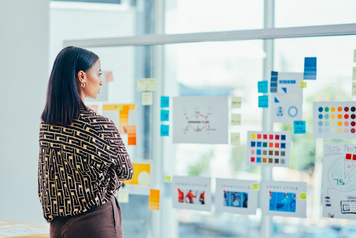 Rearview Shot Of A Young Designer Brainstorming With Notes On A Glass Wall In An Office - It's Just Elementary Advert...