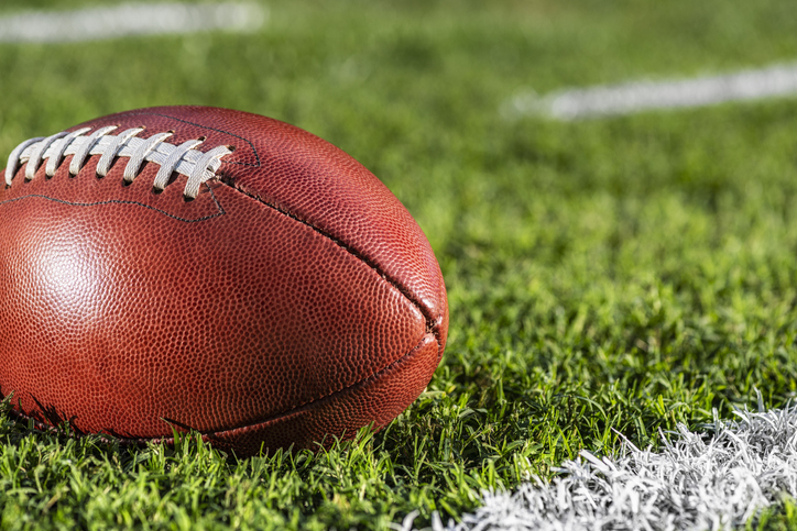 A Close Up Of An American Football Sitting Next To A White Yard Line With Hash Marks - Super Bowl Sunday: A Ratings W...