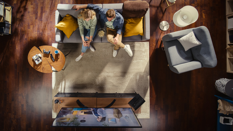 Top View Apartment: Happy Couple Watching Television In The Stylish Living Room. Looking At The Tv Display And Eating...