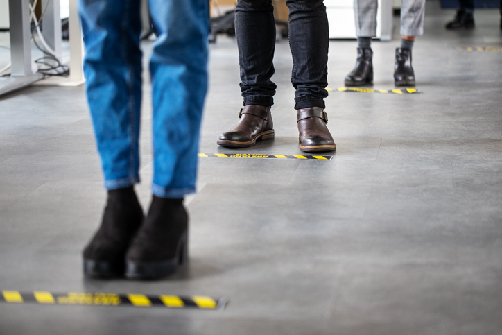 Business People Standing Behind Social Distancing Signage On Office Floor - Well, That Was Interesting. Now What?