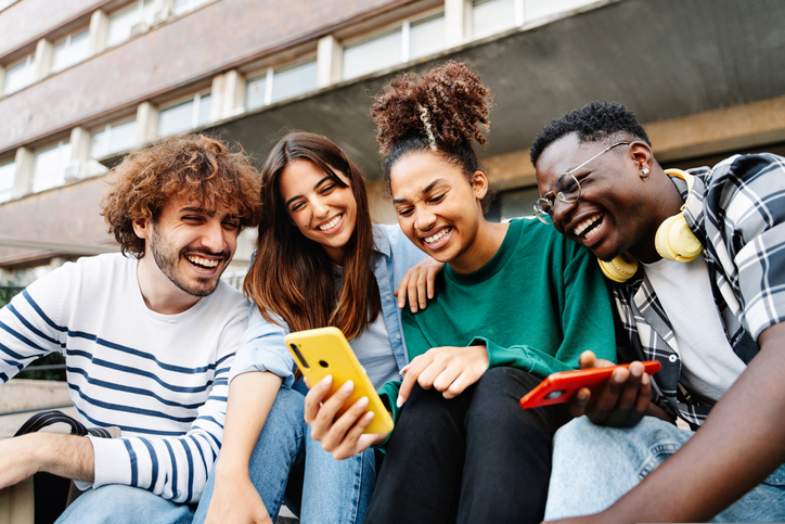 Group Of University Student Friends Sitting Together Using Mobile Phones To Share Content On Social Media - What The ...