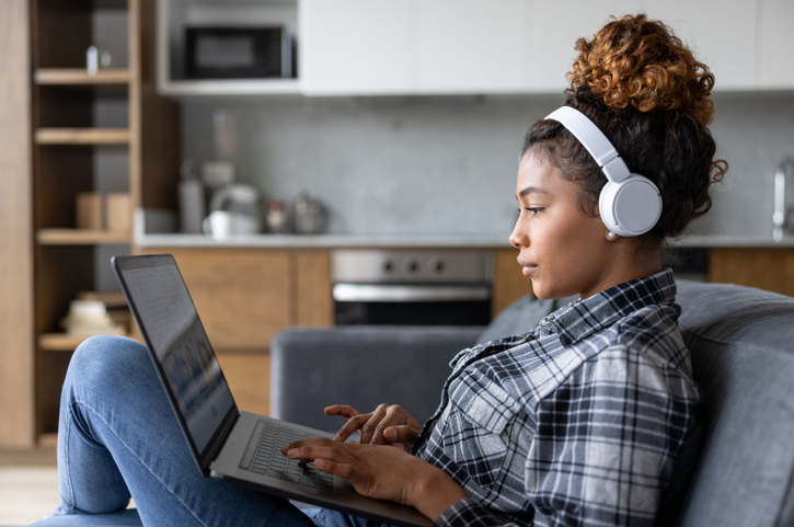 Woman At Home Working On Her Laptop And Using Headphones - Why Repetitive Advertising Forced Me TO Buy Premium Services